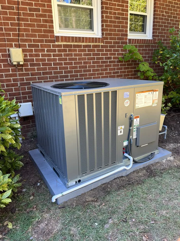 Outdoor packaged HVAC equipment beside a brick home