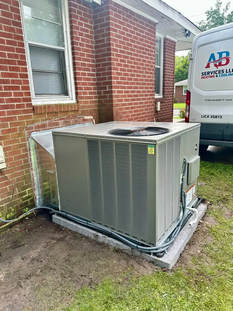 Outdoor HVAC equipment beside the AB Services service van