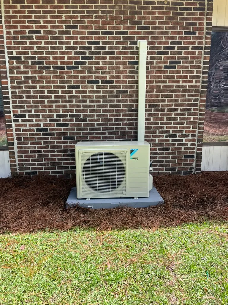 Ductless outdoor unit beside a brick home