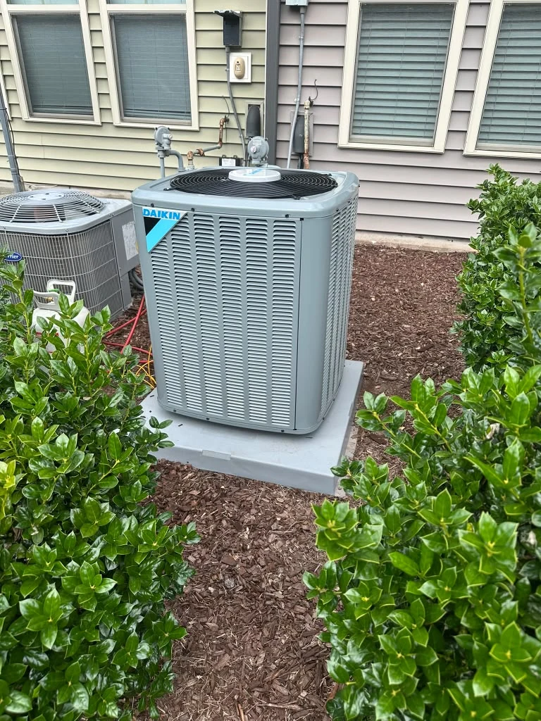 Outdoor HVAC unit beside a landscaped home