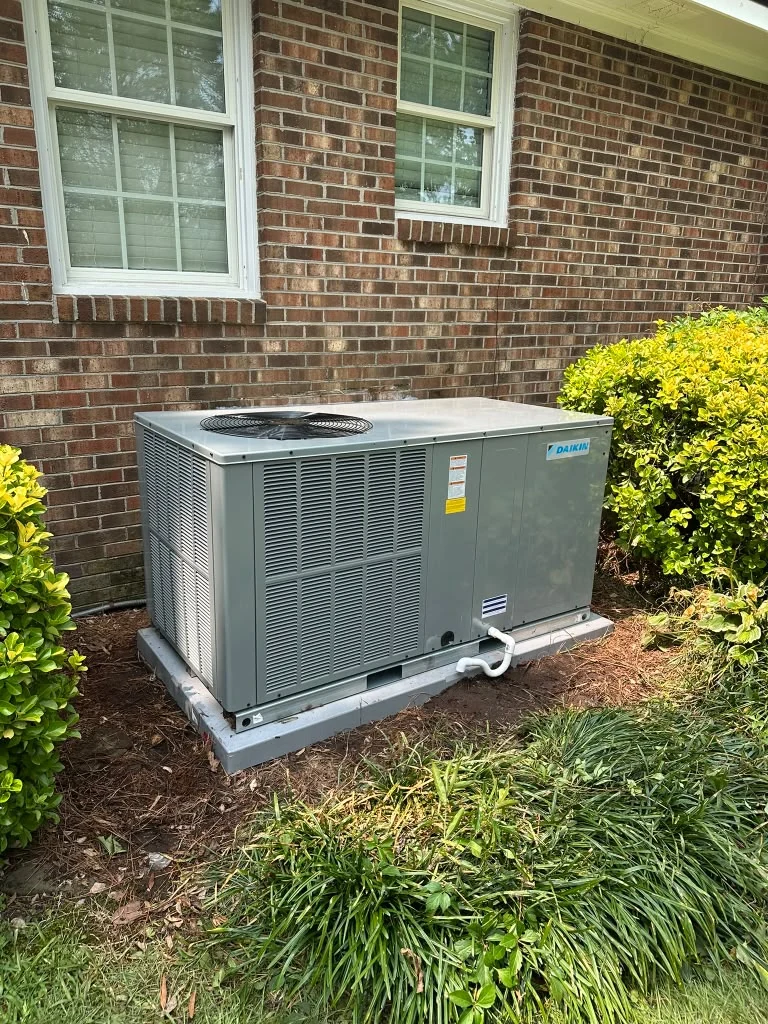 Packaged HVAC system beside a brick home